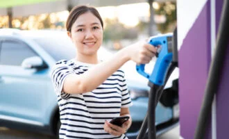 Happy Woman Holding An Ev Charger And A Phone 660 330X200